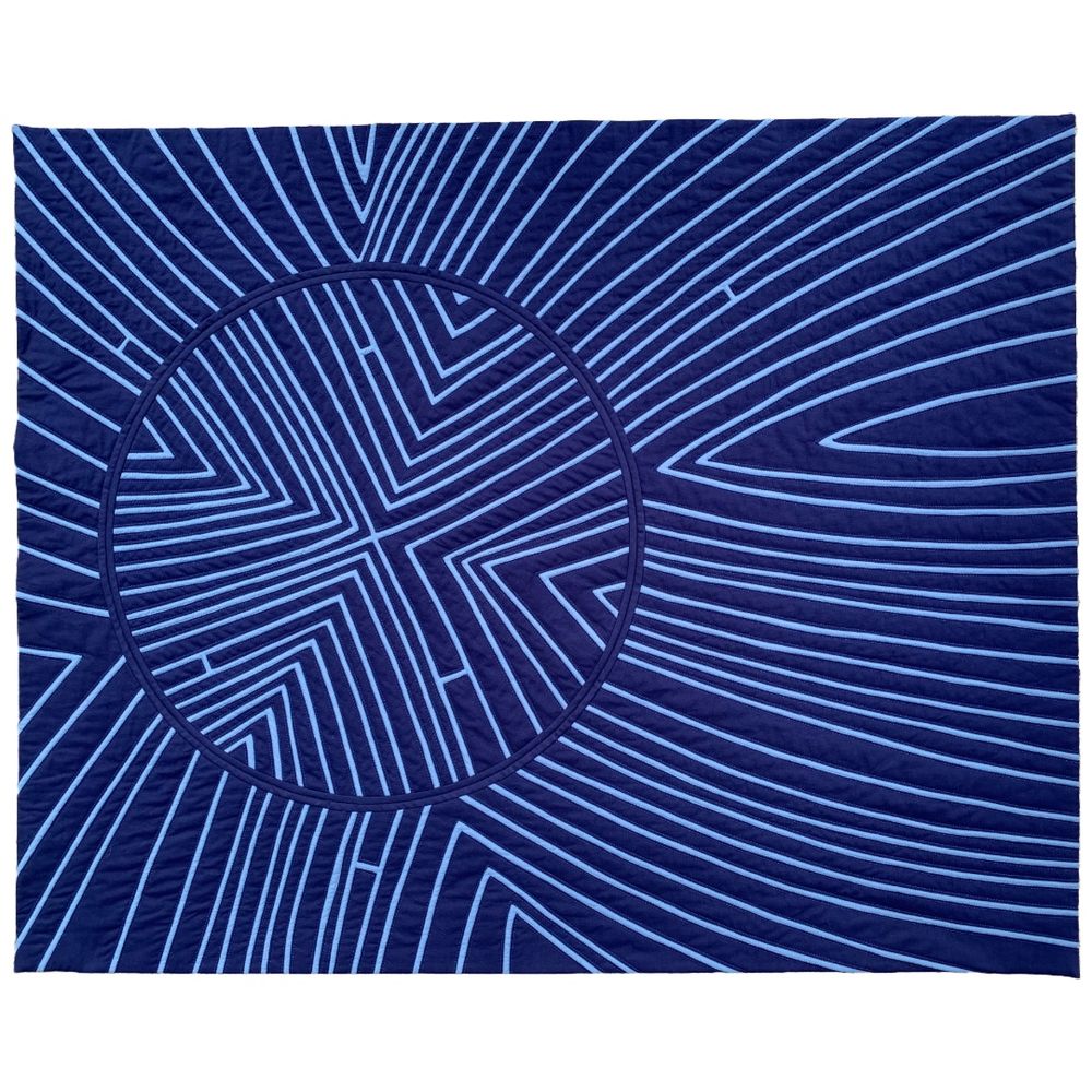 Description: Where do we connect? The top for this piece started as dark blue fabric basted over the same amount of medium blue fabric with arc-shaped lines that intersect at a single point. Each line is created by cutting a slit in the dark blue fabric and sewing down either edge with needle turn appliqué. Through this process, the quilt's personality is revealed line by line. Once quilted, the piece continues to evolve by removing a circular section of the quilt. The revolution of the inner circle breaks previous connections and forms new intersections with its current positioning. Throughout the entire construction process, none of the original fabric is removed; it is only altered, just as we change through our connections and experiences, but we continue to carry past versions of ourselves forward as we change throughout our lives.