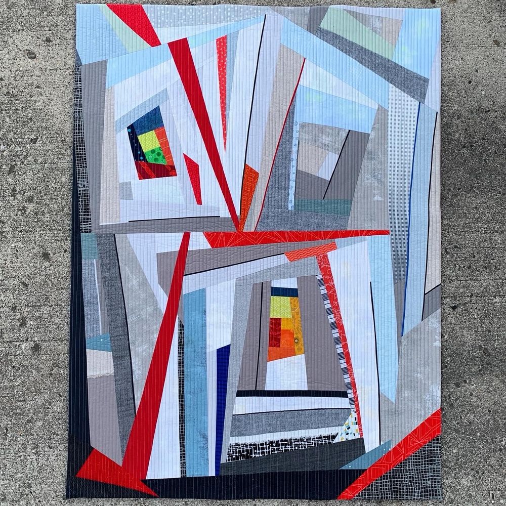 Description: Inspired by a photograph of downtown buildings, Urban Cabins is a contemporary exploration of a traditional block.  Central log cabin motifs grow improvisationally to embrace the hustle and bustle of a downtown community.  Prints, solids, cottons, and linens create diverse visual and physical textures.

