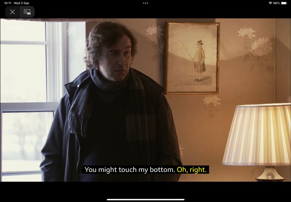 Screengrab showing Steve Coogan standing by a window in a hotel room, with subtitles saying “You might touch my bottom.” Then Rob Brydon (off camera) saying “Oh, right.”