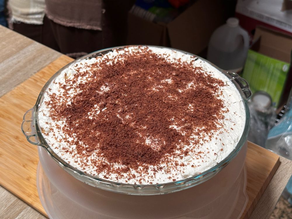 Same pie dish with fresh whipped cream and chocolate shavings added — a banoffee pie