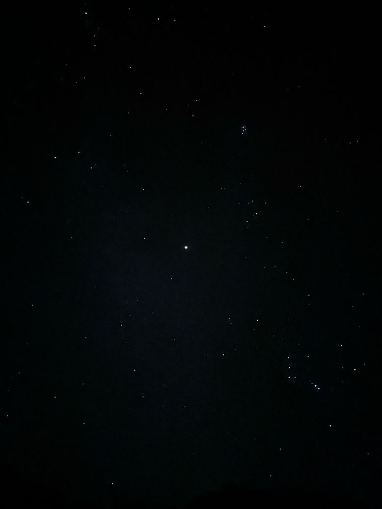 A simple photo of the stars. A bright spot in the frame's center is Jupiter, and a cluster closer to the top right corner may to be the Little Dipper (or a close approximation).