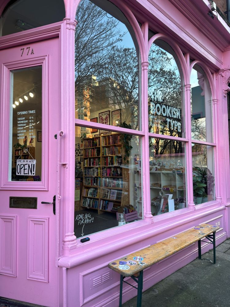 The Bookish Type shop in Leeds, a bright pink shopfront with a sign that reads "The Bookish Type: queer indie bookshop". 