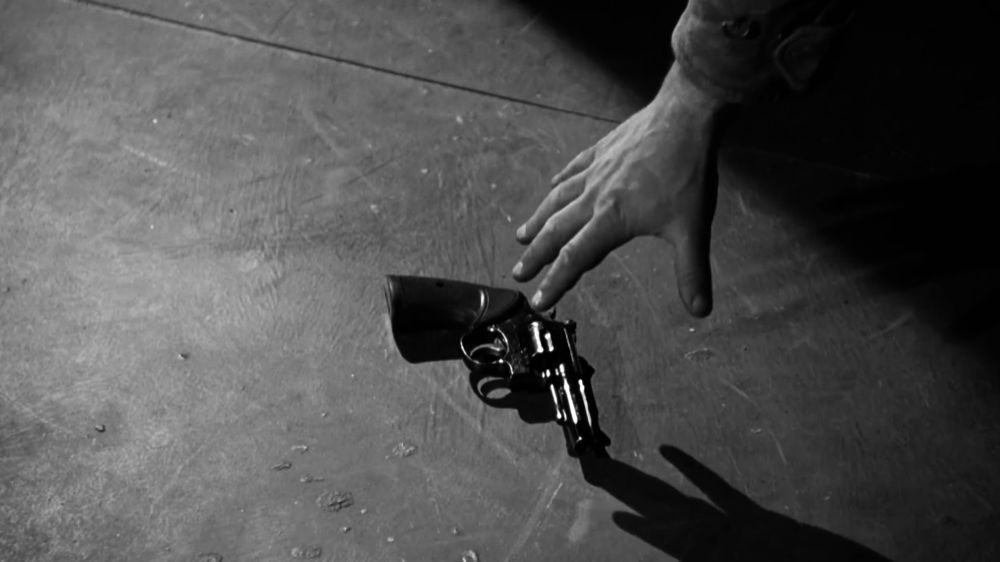hand reaching for gun in intro, light casting bold shadow across the frame. in black and white