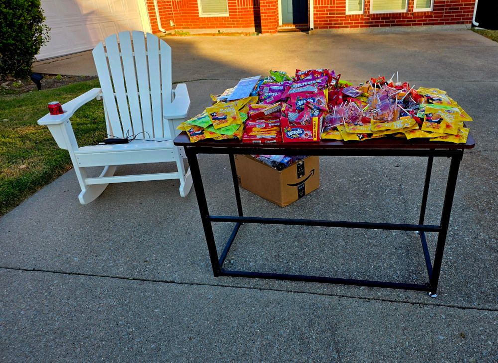 A table with a ton of candy and a rocking chair 