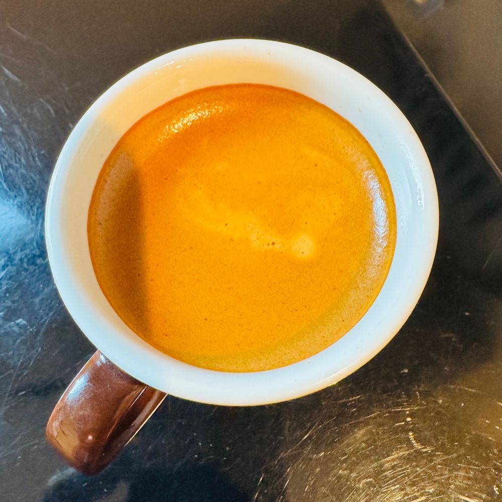 A cup of espresso on a black surface.