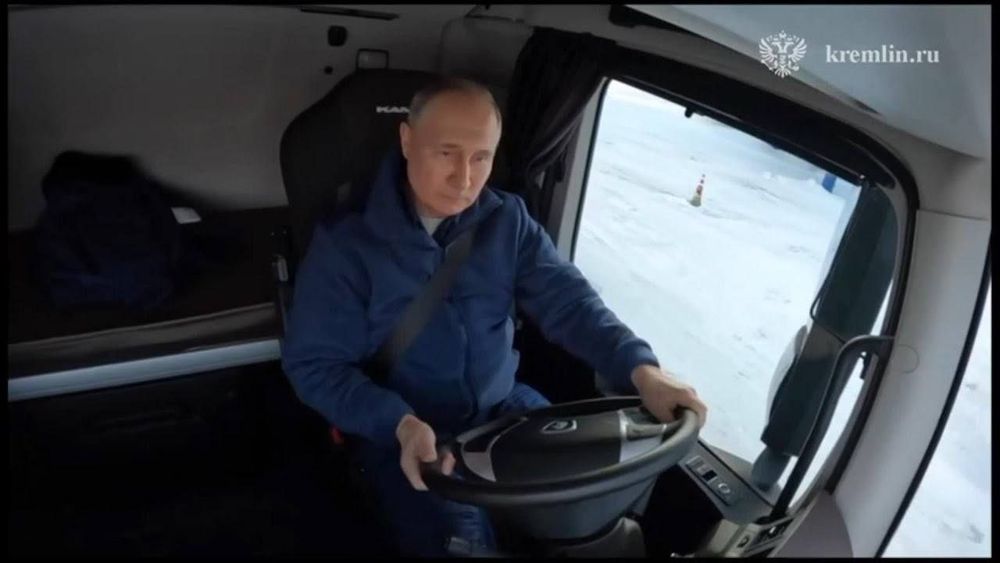 Putin sitzt im Cockpit eines LKWs am Lenkrad.
