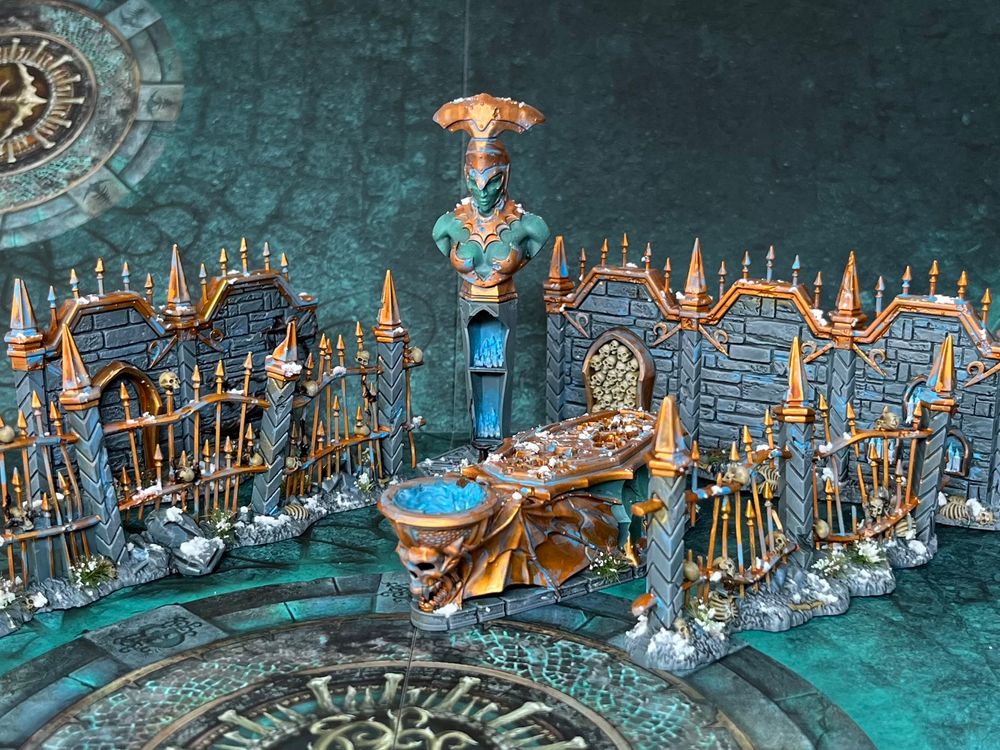Blood and sand terrain set - railings and walls with a statue and sarcophagus in grey, copper and teal with snow basing