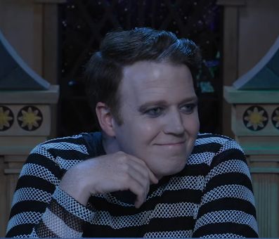 my boy brennan lee mulligan wearing a black and white striped mesh shirt with shadows around and under his eyes, smiling an impish smile.