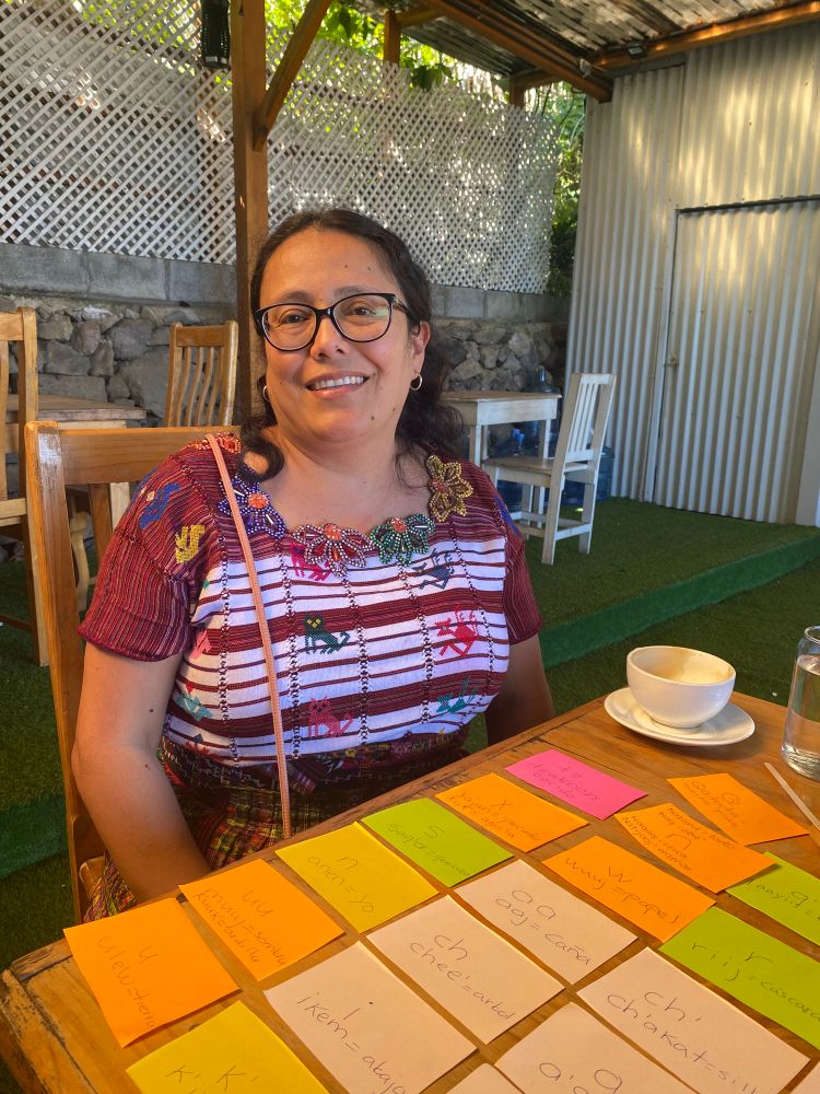 Photo of Mayan woman wearing traditional clothes and a bunch of brightly colored flash cards of sounds and vocab words. 
