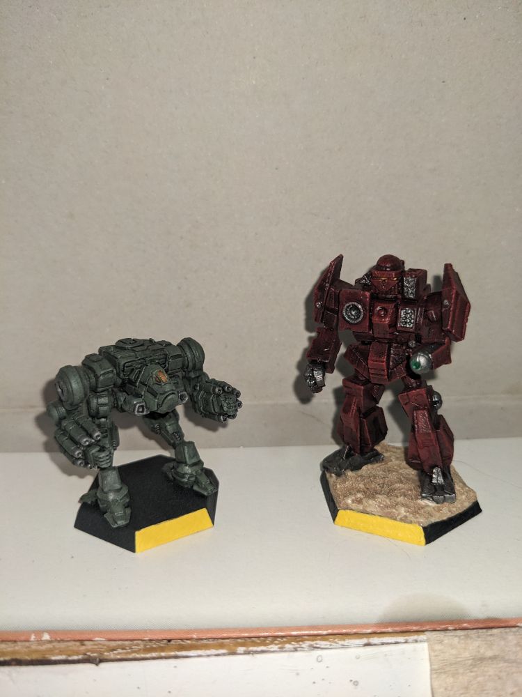 On the Left is a Military Green colored Nova Battlemech beside a dark red Charger Battlemech