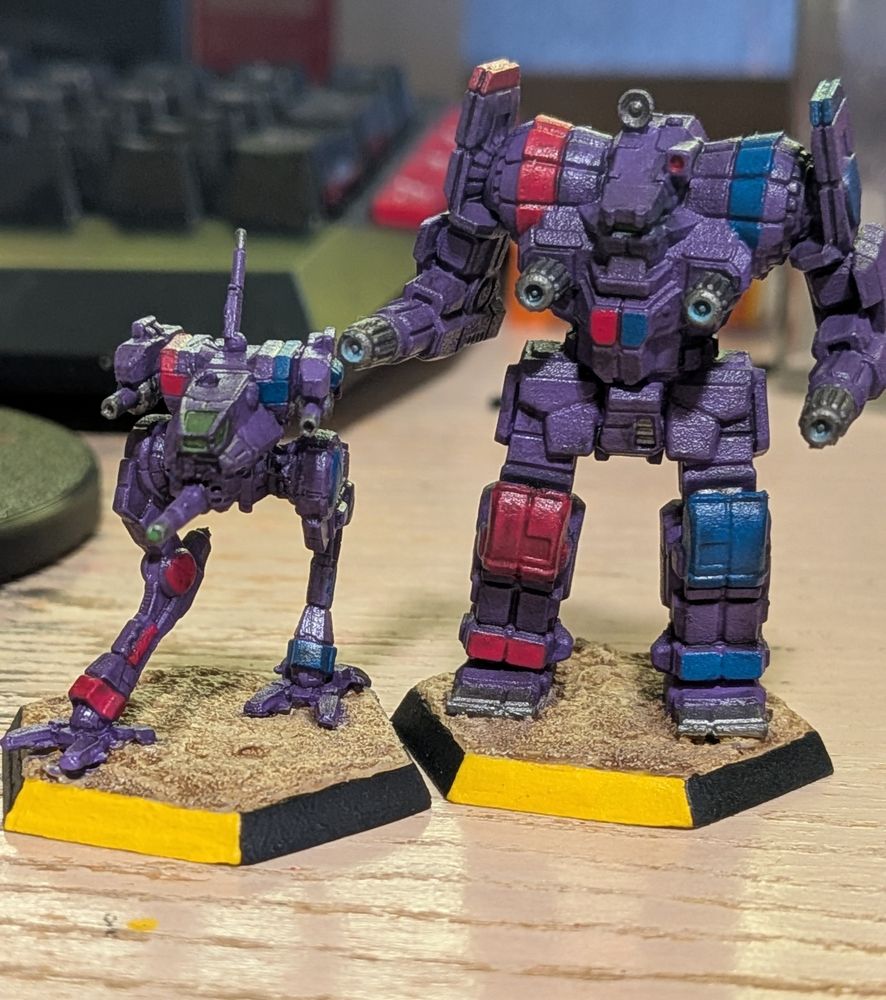 A Locust and an Awesome Battletech miniature. Both are painted in the colors of the Marik Militia (Purple, Red, and Blue).