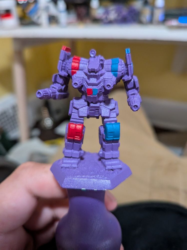 An IWM Awesome miniature primed Alien Purple. The paint scheme features blue and red highlights in the style of the Marik Militia. This specific model is the AWS-9Q variant.