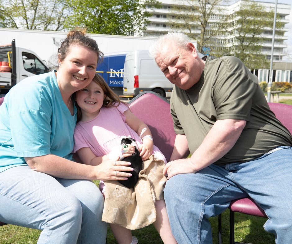 A family of three sit with a guinea pig
