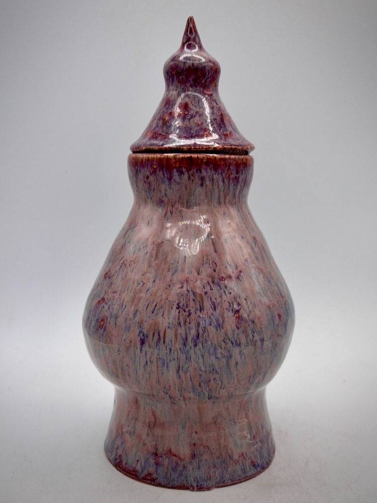 A lilac coloured urn with a pointy top in various shades of purple.