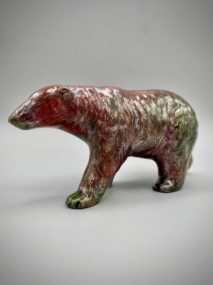 A raku pottery bear with splashes of red and green, right side pose.