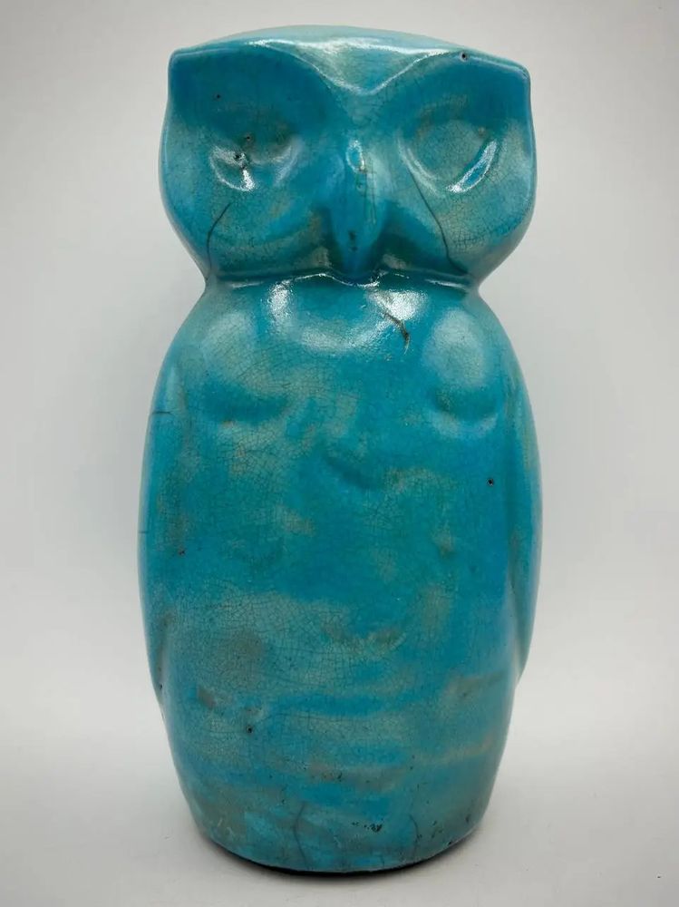 A turquoise ceramic owl with the distinctive black cracks and lines from the raku pottery process