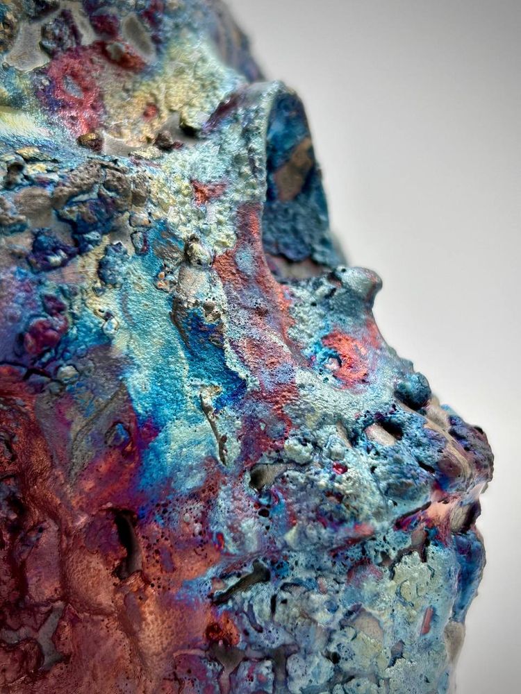 A raku skull with glazes in red, purple, blue and charcoal black. Close-up of the area around the mouth.