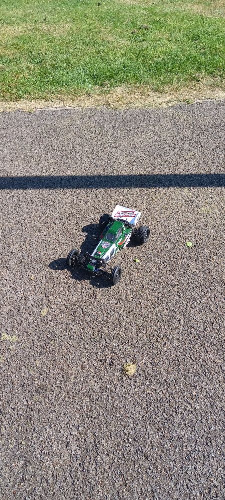 A green and white RC car sat on tarmac.