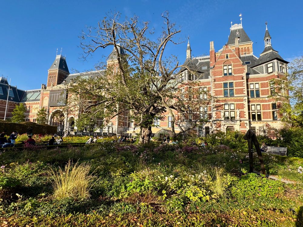Front facade of the Rijksmuseum and gardens lit by afternoon sun.