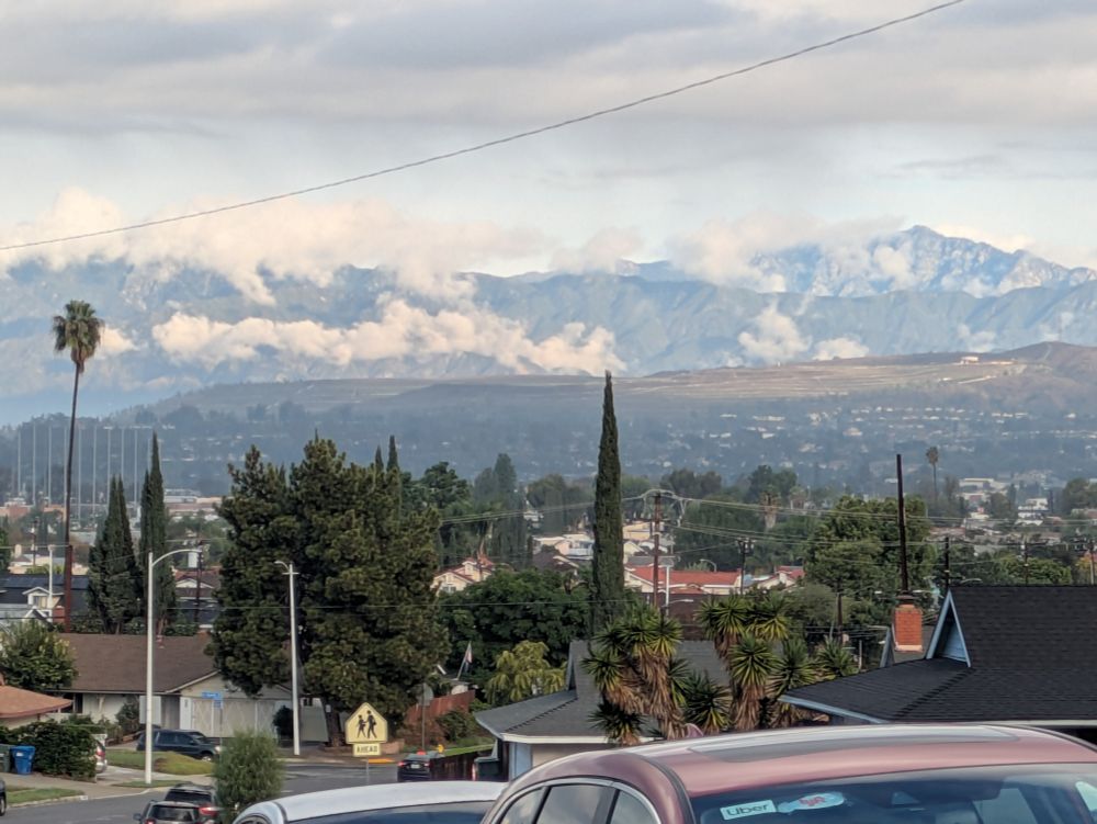 Trees in the foreground with rolling hills covered with thin strands of clouds in the background.  This is the peak of suburban quaintness.  Butalso, suburbs suck.