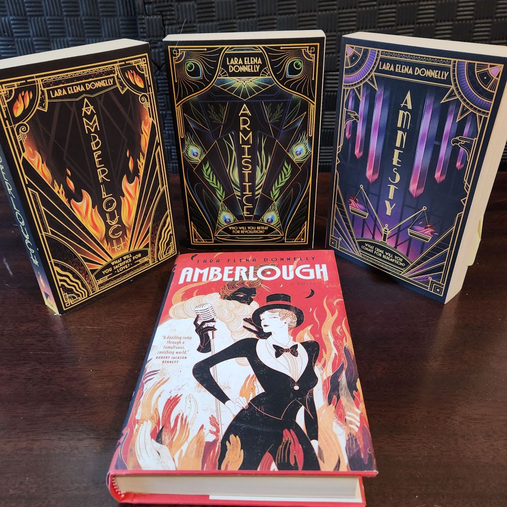 The books of the Amberlough Dossier trilogy: the hardcover edition and three books in paperback: Amberlough, Armistice, and Amnesty. 