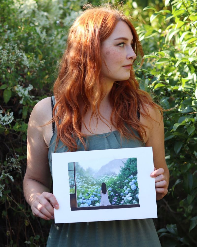 the artist holding an original painting