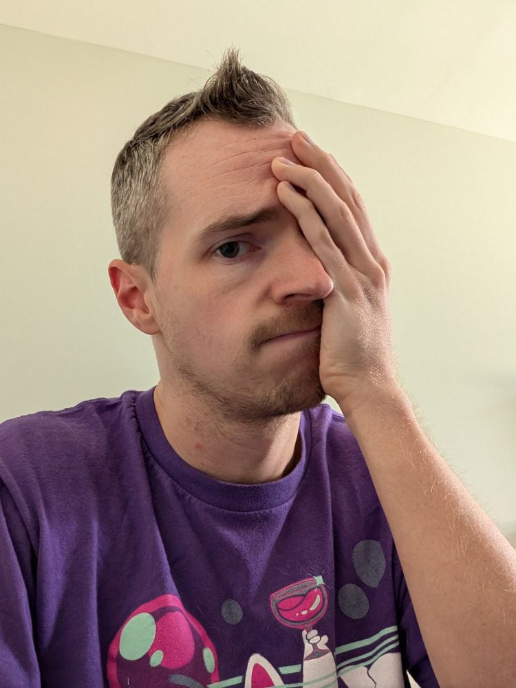 Tired gay man with one hand over his face and a weary expression