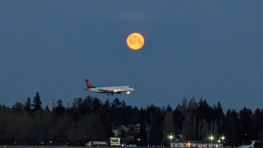 a delta aircraft landing under a full moon