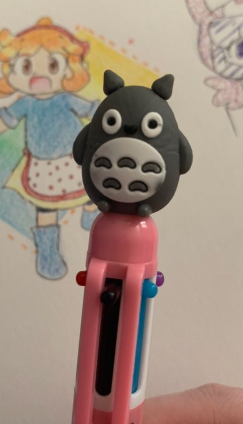 A very silly looking Totoro bootleg pen, with several sketchbook drawings of various Pop’n Music characters in the background