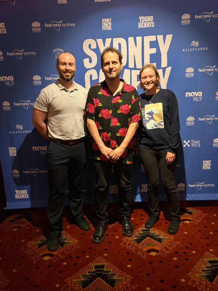 Left to right: my brother, then Adam Kay, then me. I’m smiling so widely I have dimples and squinty eyes.