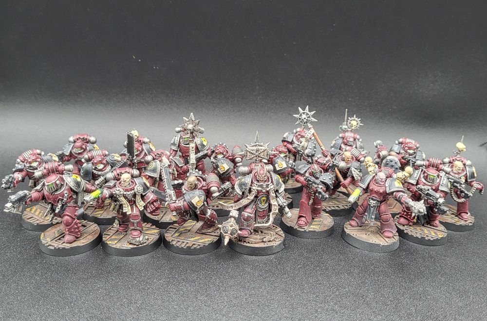 A group of painted Word Bearers space marines for Warhammer: The Horus Heresy. They are painted in red and black and mounted on brown metallic industrial bases. 