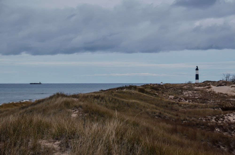 Behold grassy dunes, Lake Michigan, a freighter along the horizon, and the lighthouse in the distance observing all that passes. 