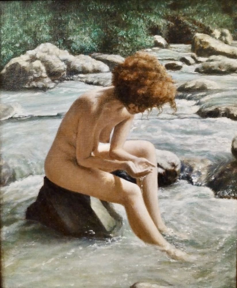 A painting of a nude female figure sitting on a rock in a stream. She is looking down at her cupped hands bringing up some water. She has bushy brown hair.