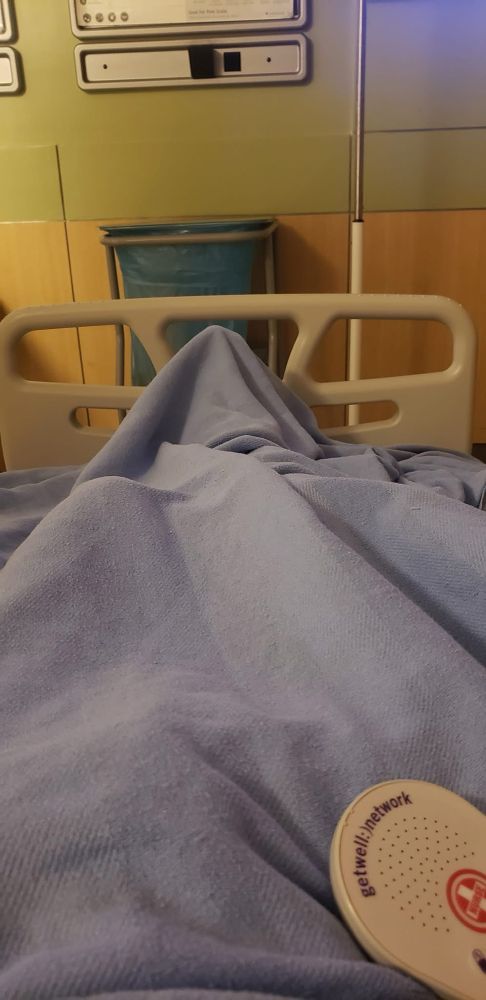 my legs covered up with a blue hospital blanket, while chilling in the hospital. emergency clicker button included 😂