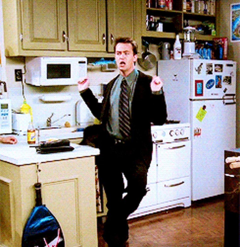 a man in a suit and tie is standing in a kitchen with a microwave and refrigerator