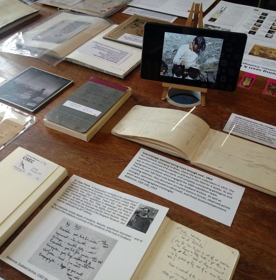 A wooden table filled with historic books and documents alongside explanatory labels at the Sedgwick Museum archive.