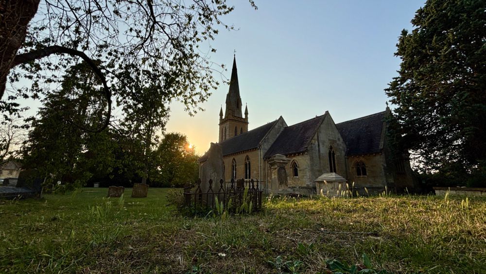 St David’s Churchyard, Moreton in Marsh, with the spire of the church silhouetted against a sunset on a hot summers evening 