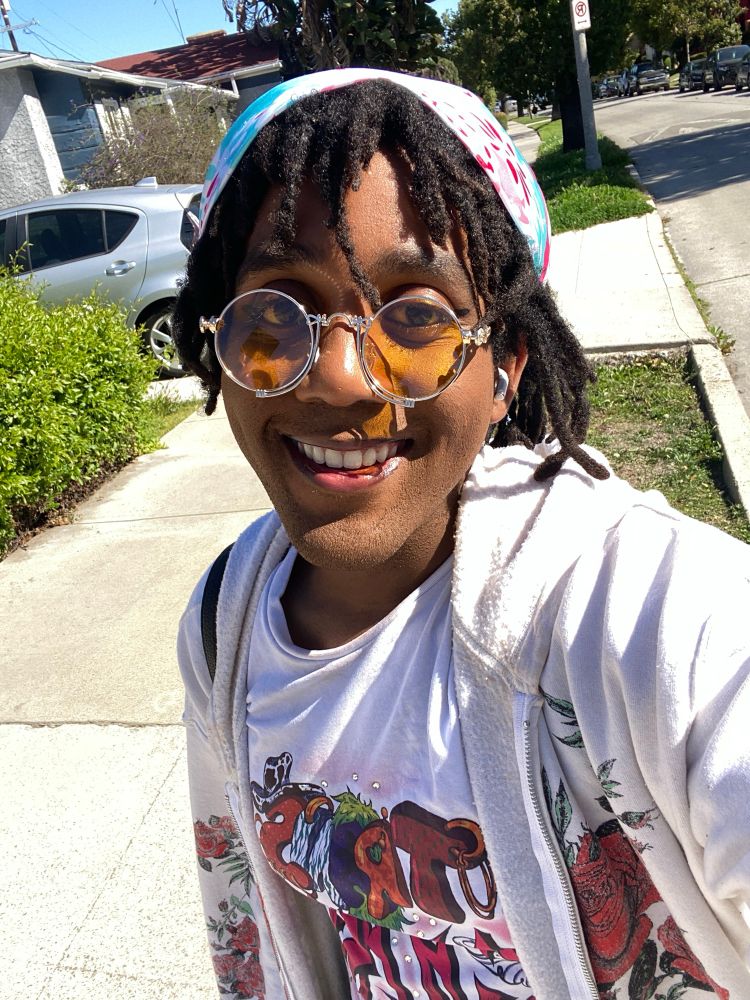 Jasmine wearing a shirt that reads “trans chaos” in graffiti letters