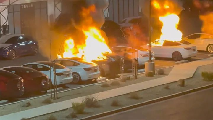 A row of Tesla vehicles on a lot, several of which are engulfed in the beautiful orange flames of creative destruction.