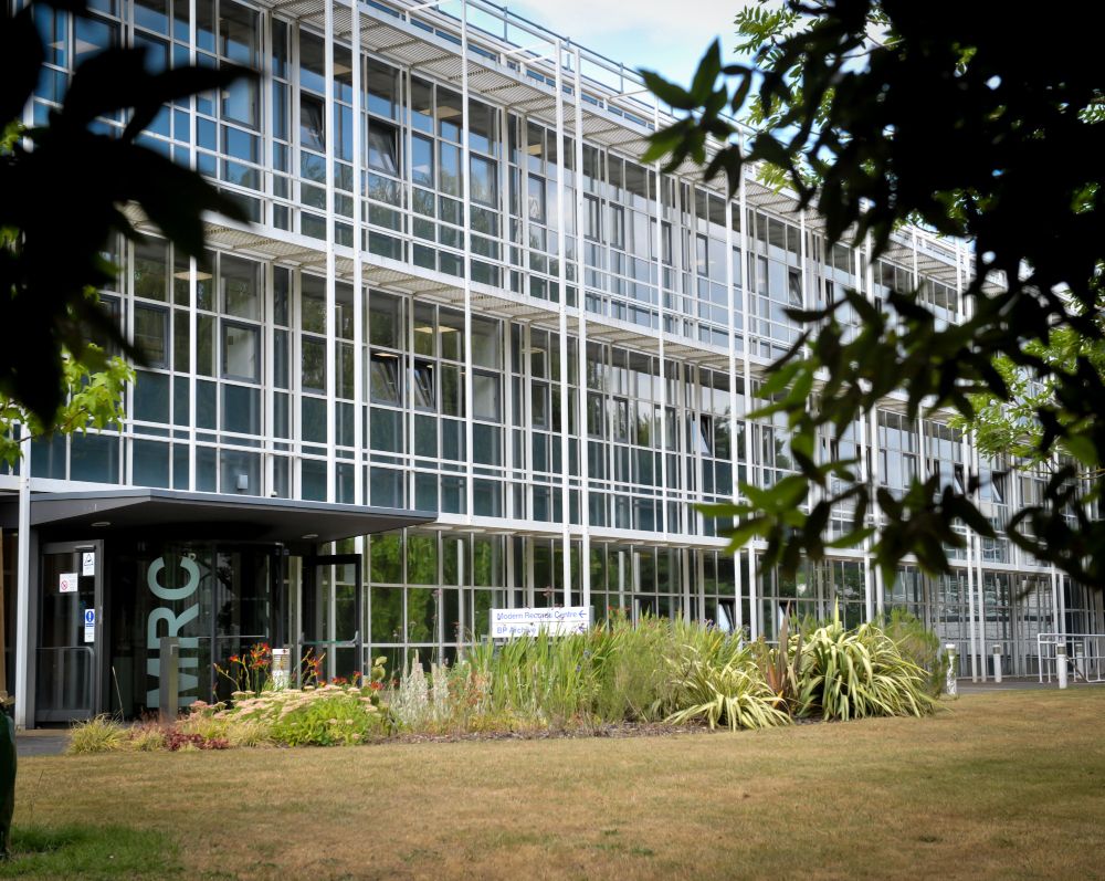 Photograph of the exterior of the Modern Records Centre, a glass panelled building with the letters MRC written on the entrance hall and a flower bed and lawn to the front of the entrance.