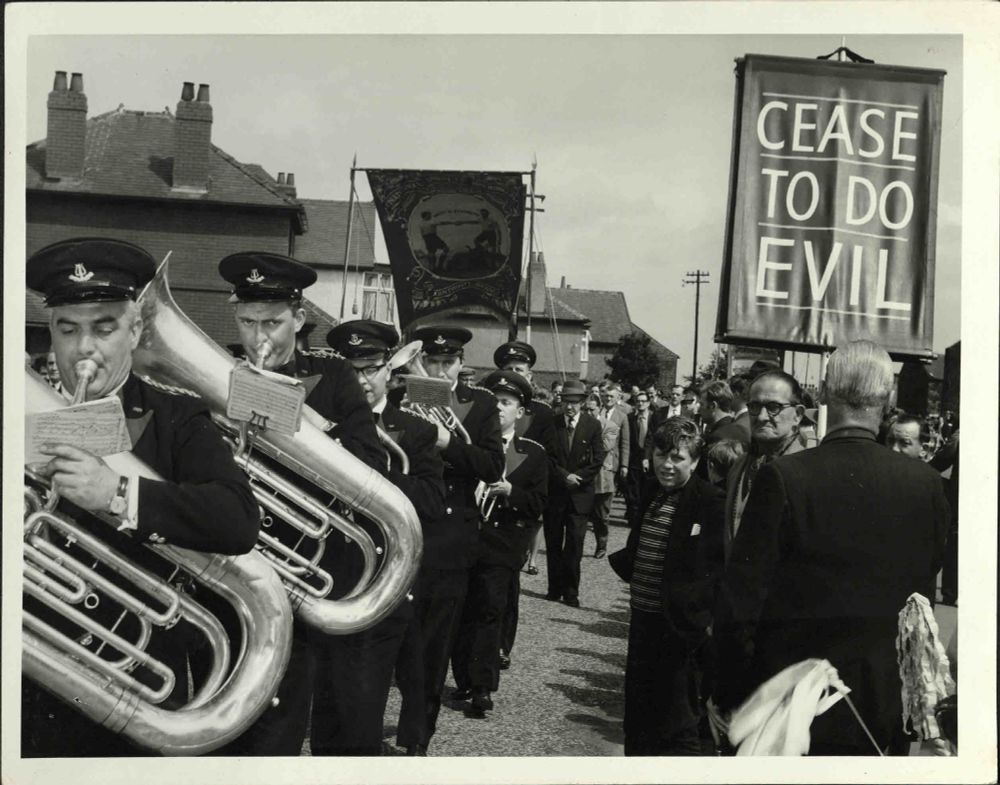 Photograph of parade at 1965 Yorkshire Miners' Annual Demonstration, held in Barnsley. Members of the parade include a brass band and bearers of the National Union of Mineworkers Armthorpe branch banner.