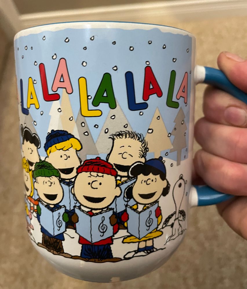A Christmas coffee mug of the Peanuts gang (Charlie Brown, Snoopy et al) singing “fa la la la la la la la la”