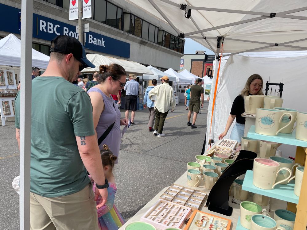 People looking at a booth with pottery