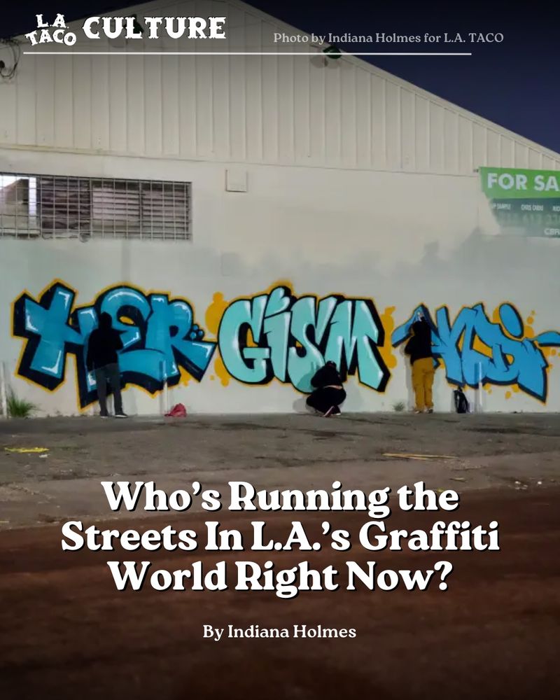 Photo of three graffiti artists using various shades of blue to paint on a warehouse wall at nighttime. 

Bottom half of image features title for article “Who’s Running the Streets In L.A.’s Graffiti World Right Now?” Below that in smaller font it reads “By Indiana Homes” 