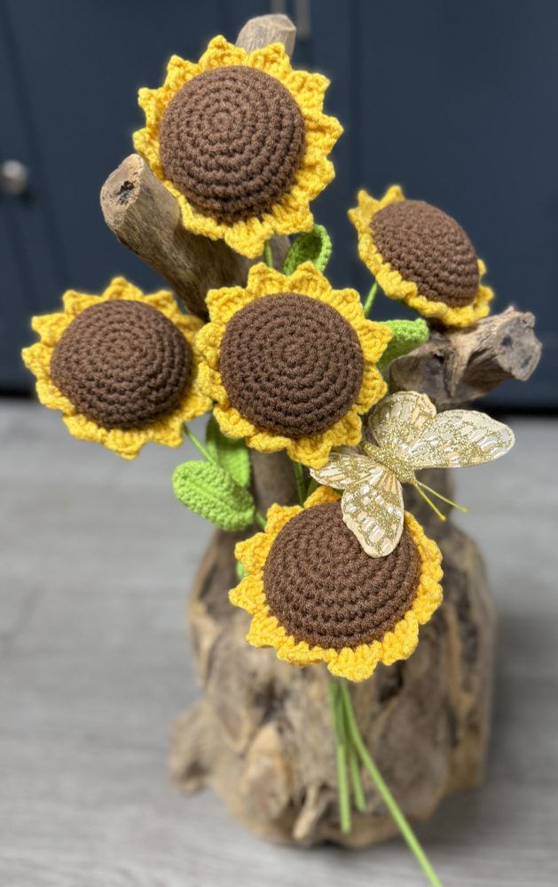 A small sheaf style spray of crocheted sunflowers tied with a glittery butterfly nestled among them. 