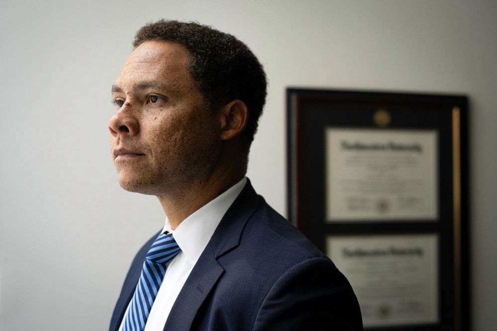 A portrait of a man wearing a blue suit looking off to the left side of the frame.