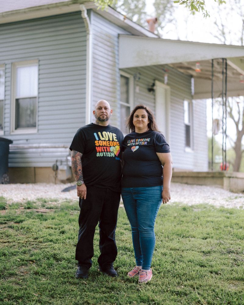 A photo of two people standing in the green in front of a house.