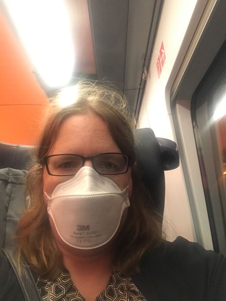 Ich, eine blonde Frau mit schwarzer Brille, mit FFP3-Maske im Zug.