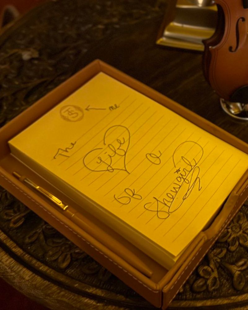 A yellow notepad with handwritten words “The life of a Showgirl” and some doodles. The word life is inside a heart.