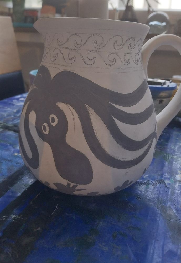A wip of a ceramic water jug being painted inspired by the Minoan maritime Style. The main object of the painting being an upside-down octopus.